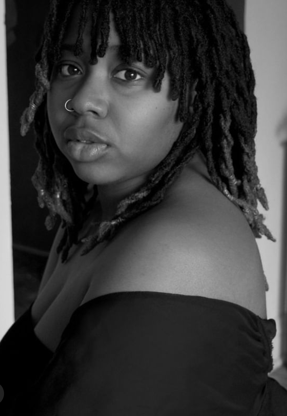 portrait photo noir et blanc de 𝐆𝐚𝐛𝐫𝐢𝐞𝐥𝐥𝐞 femme noire cheveux aux épaule en locks, un chandail noir laissant les épaules nues.